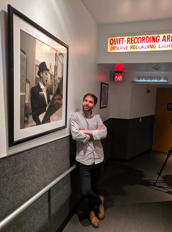 Charles McDonald standing next to a photograph of Paul McCartney at Capitol Records after a recording session.