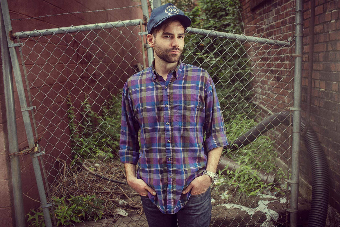 Charles McDonald wearing a trucker hat and standing next to a chainlink fence